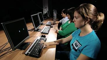 Drei Frauen sitzen vor Computerbildschirmen