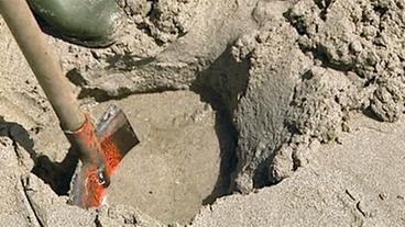 Schaufel gräbt Loch im Sand