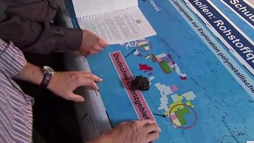Forscher an Karte des Pazifiks, auf der Lizenzgebiete eingezeichnet sind