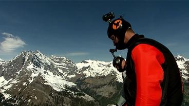 Zwei Männer stehen in Wingsuits an der Kante einer Felswand