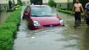 Bild: Amateuraufnahme Menschen stehen bis zu den Knien im Wasser, ein Auto ist halb versunken
