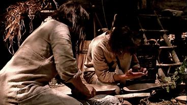 Nachgestellte Szene, zwei Steinzeitmenschen bereiten Essen zu