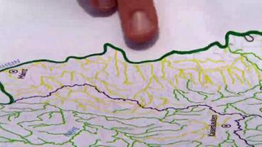 Ein Finger zeigt auf eine Karte mit dem Flusssystem des Rheins