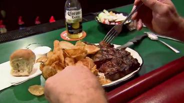 Mann sitzt an Theke und isst ein Steak.