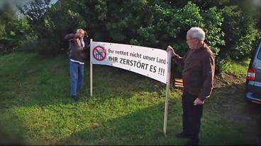 Zwei Männer halten ein Protestplakat