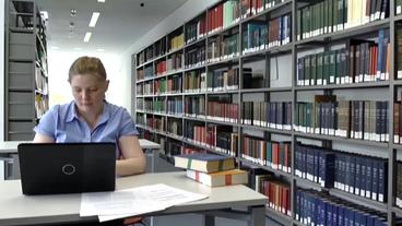 Professorin Binnewies arbeitet am Laptop in Bibliothek