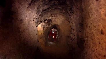 Ein Mann kriecht durch einen Tunnel eines Erdstalls