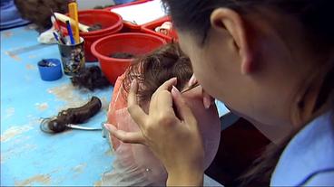 Chinesin knüpft Haare in eine Vorlage.