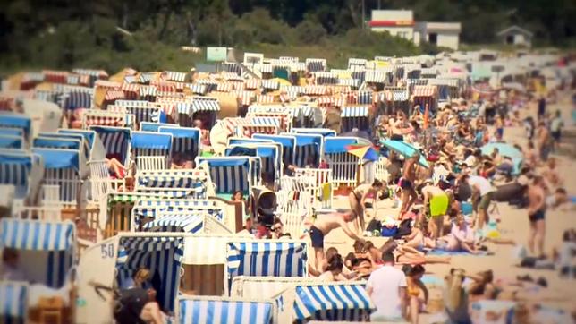 Viele Strandkörbe und Menschen in Sommer an einem Strand.