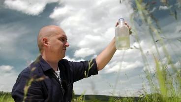 Ein Wissenschaftler hält eine Wasserprobe in der Hand.