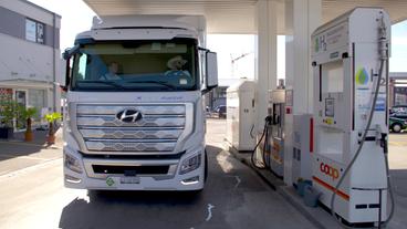 Weißer LKW mit Brennstoffzellen-Antrieb fährt an Wasserstoff-Tankstelle 