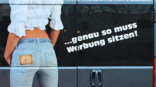 Werbung mit einer Frau von hinten auf einem Lieferwagen