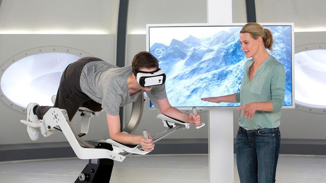 Bild: ARD/Michael Boehme Computerspiele werden landläufig mit Bewegungsmangel in Verbindung gebracht. Doch ein neuartiges Spielsystem kombiniert VR-Brillen mit einer Ganzkörper-Bewegungssteuerung. So sollen spielerisch fast alle Muskelpartien beansprucht werden. Wie das genau funktioniert, testen Anja Reschke und Adrian Pflug in "Wissen vor acht – Zukunft".