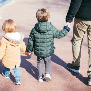 Kinder laufen an der Hand eines Erwachsenen