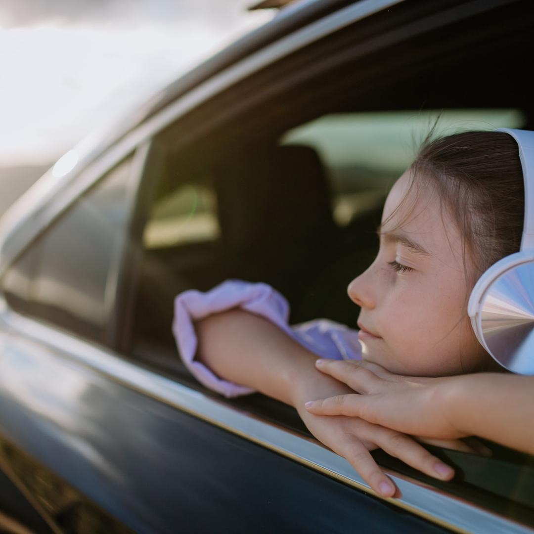 Mädchen hört im Auto mit dem Kopfhörer Geschichten