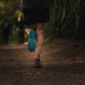 Die Beine eines Läufers im Wald.