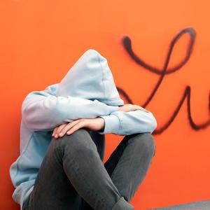 Symbolbild Liebeskummer: Ein Junge sitzt traurig vor einer Wand