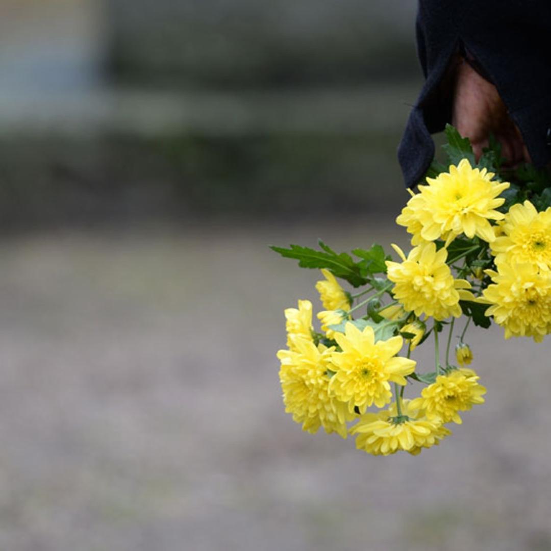 Mit einem Strauß Blumen in der Hand steht ein Mann vor einem Gedenkstein in Teltow (Brandenburg) am 27.01.2015