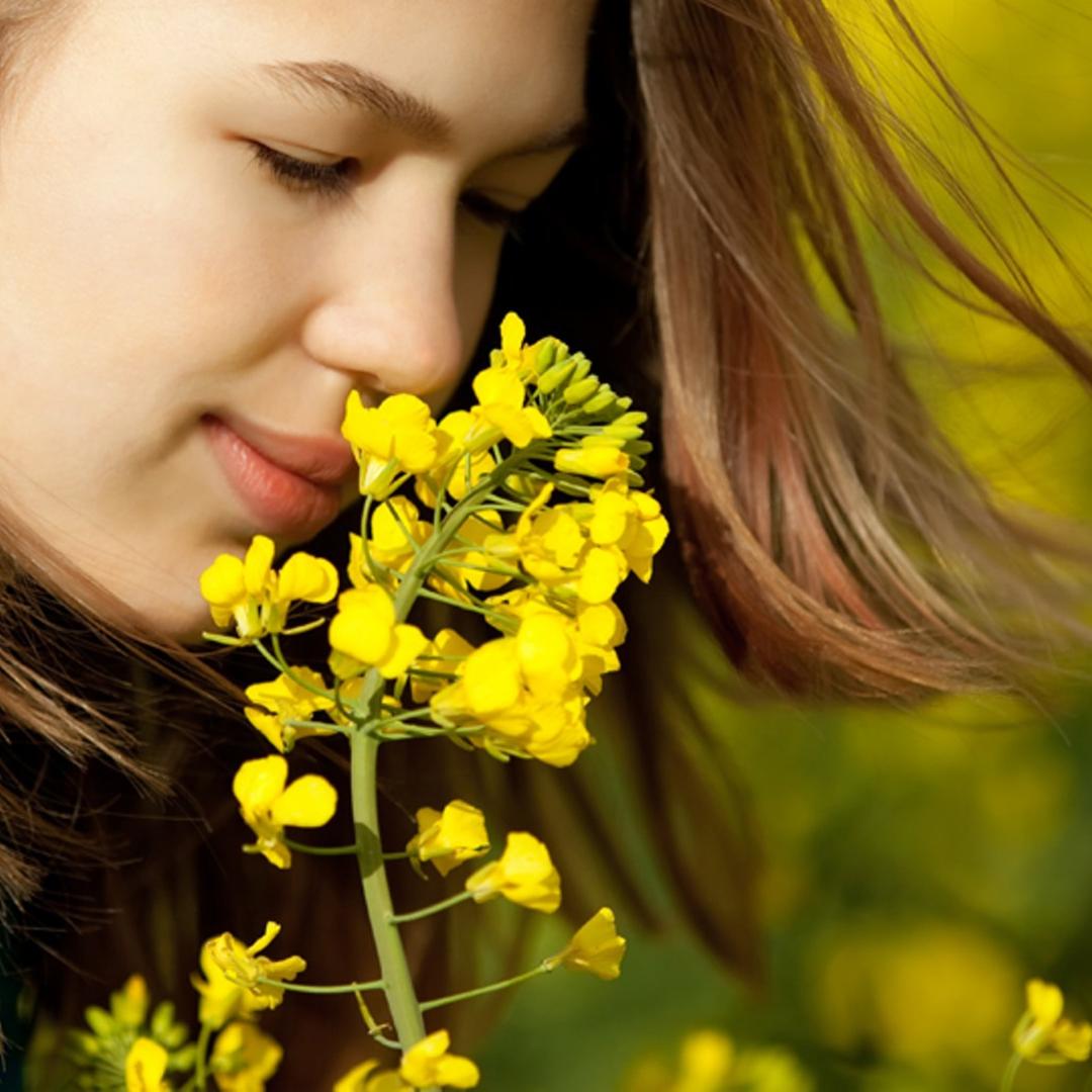 Ein Mädchen riecht an einer Blume.