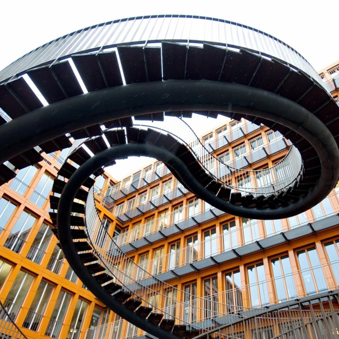 Geschwungene, freistehende Treppe vor Gebäudekomplex Geschwungene, freistehende Treppe vor Gebäudekomplex