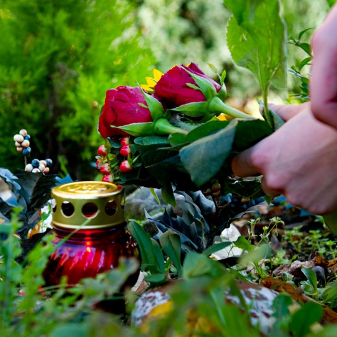 Eine Frau legt Blumen auf ein Grab