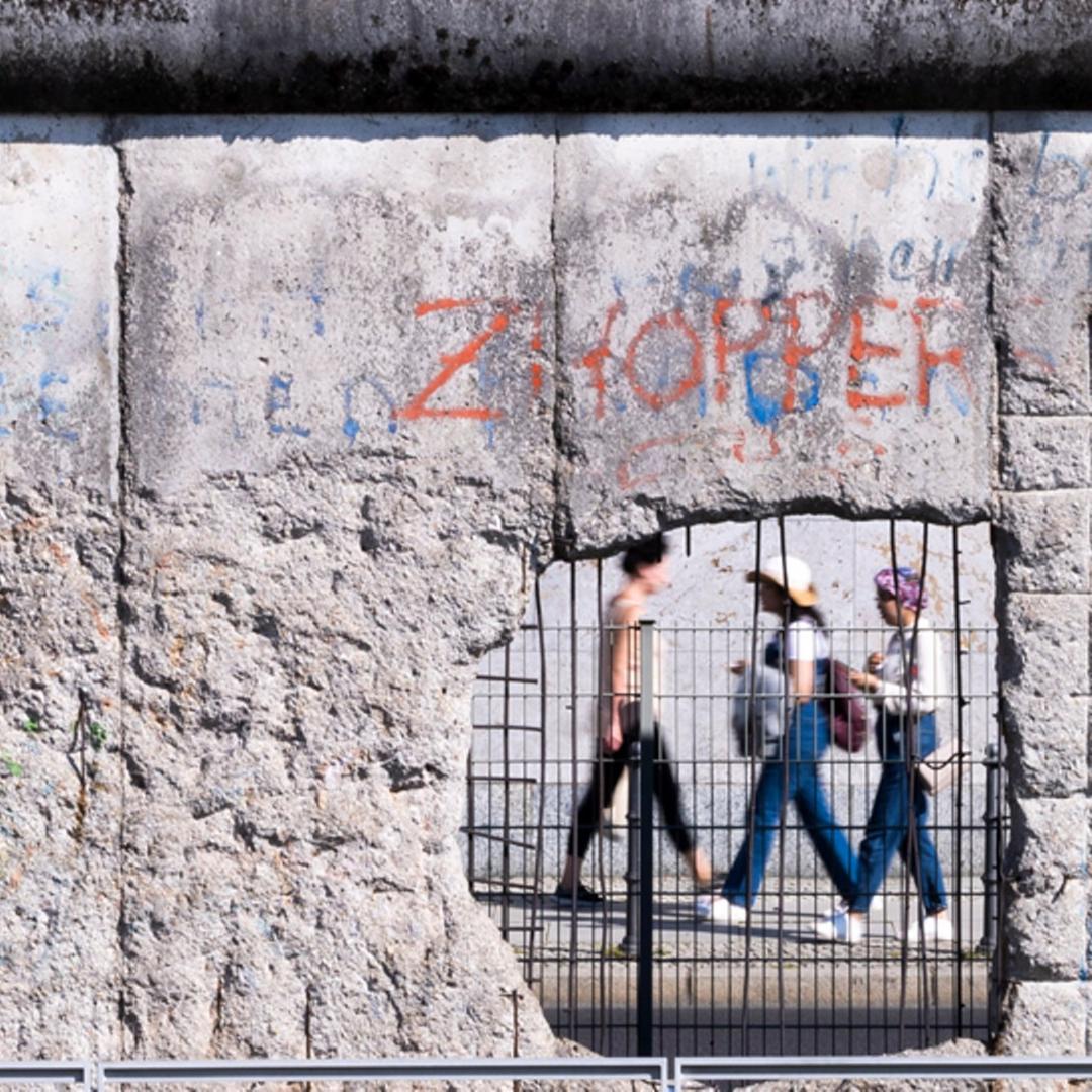 Passanten sind durch ein Loch in einem verbliebenem Stück der Berliner Mauer an der Niederkirchnerstraße zu sehen