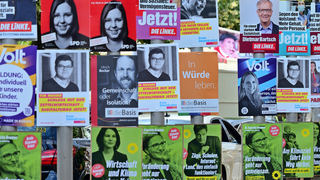 An Straßenlaternen hängen zahlreich Plakate von verschiedenen Parteien.