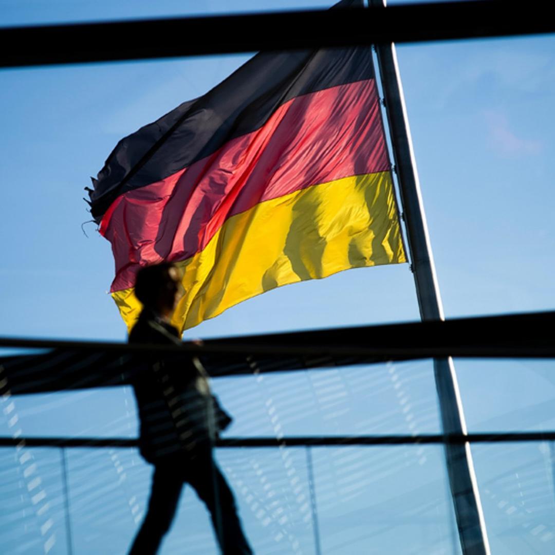 Eine Frau läuft am 15.05.2015 durch die Kuppel des Reichstags in Berlin. Im Hintergrund weht eine Deutschlandfahne. 