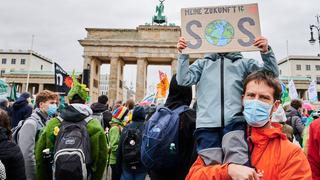„Meine Zukunft SOS“ steht auf einem Transparent, das ein Kind vor sein Gesicht hält, während es bei seinem Vater vor dem Brandenburger Tor auf den Schultern sitzt. 