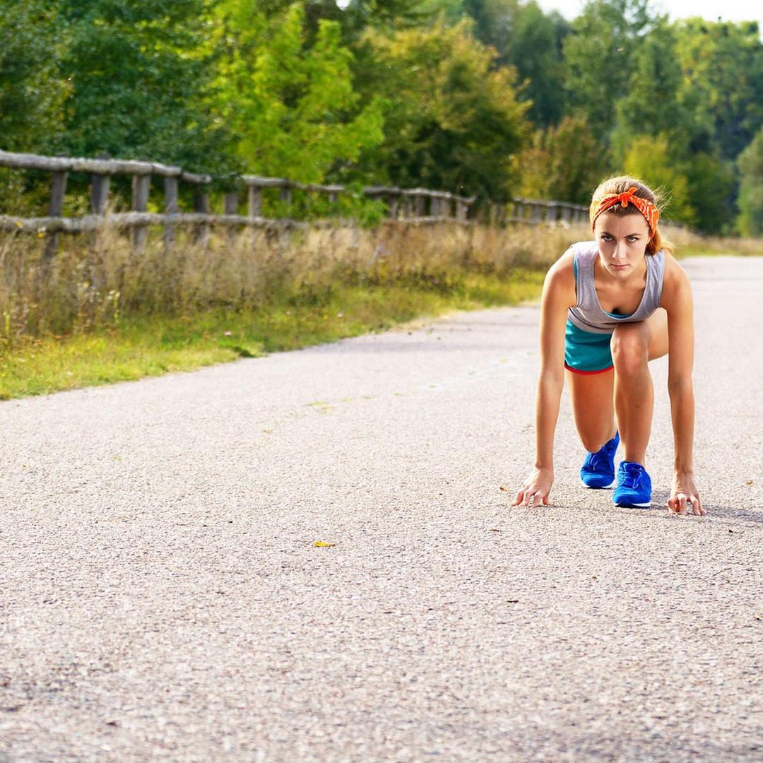 Eine Joggerin in Startposition auf einer Landstraße.・Bild: Eine Joggerin in Startposition auf einer Landstraße. Eine Joggerin in Startposition auf einer Landstraße.
