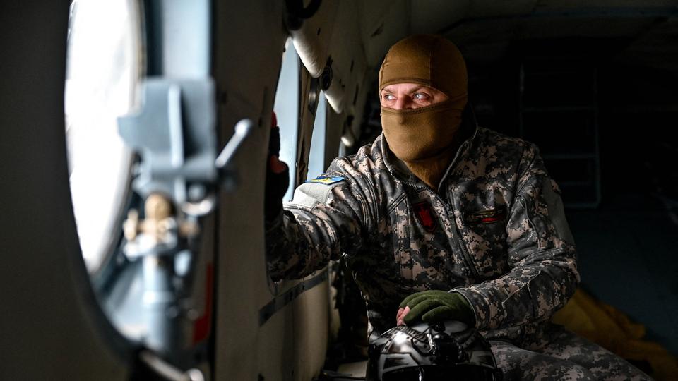 Ukrainischer Soldat blickt durch Hubschrauberfenster.