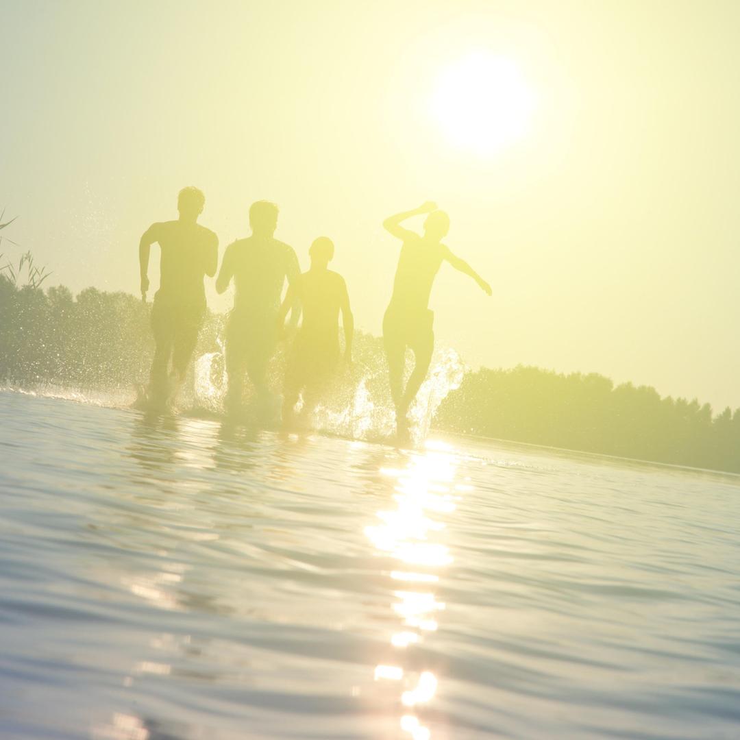 Eine Gruppe von Leuten rennt durchs Wasser in der Abendsonne