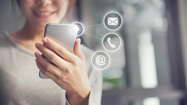 Bild: Getty Images/oatawa Zuschauer sieht auf ein Smartphone das ein Kommuniktionsmittel zur Kontaktaufnahme darstellt.