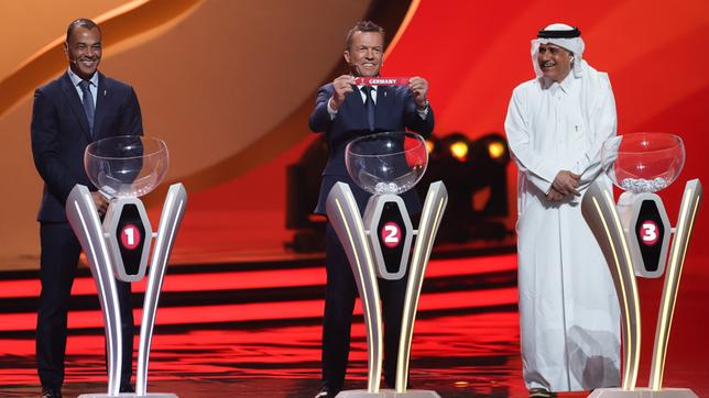 Bild: dpa/Christian Charisius Auslosung der WM-Vorrunde am 1. April 2022 in Doha. Lothar Matthäus (M) hält das Los von Deutschland in den Händen.
