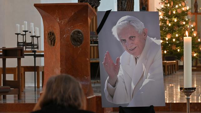 Eine Frau betet vor einem Bild des verstorbenen emeritierten Papst Benedikt XVI. in der Frauenkirche in München. Der emeritierte Papst Benedikt XVI. ist am 31.12.2022 im Alter von 95 Jahren im Vatikan gestorben. 