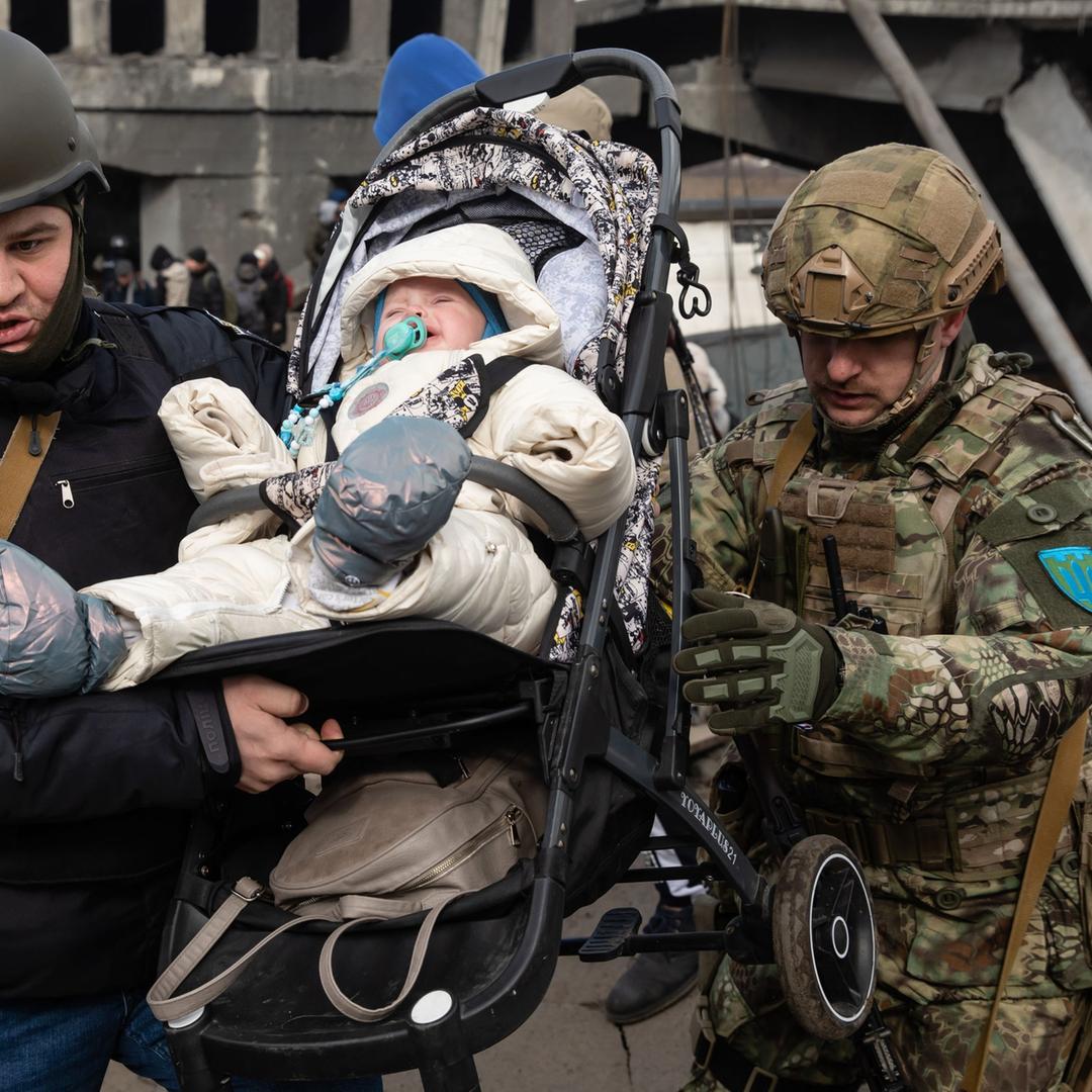 Irpin, Ukraine: Soldaten tragen ein Kind in seinem Kinderwagen während der Evakuierung.