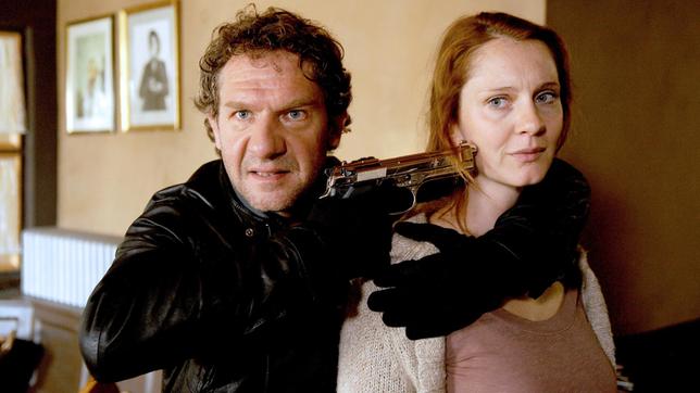 Bild: ARD Degeto/Hans-Joachim Pfeiffer Der Gangster Daniele (Johannes Zeiler) möchte sich mit Petra (Daniela Schulz) als Geisel freipressen.