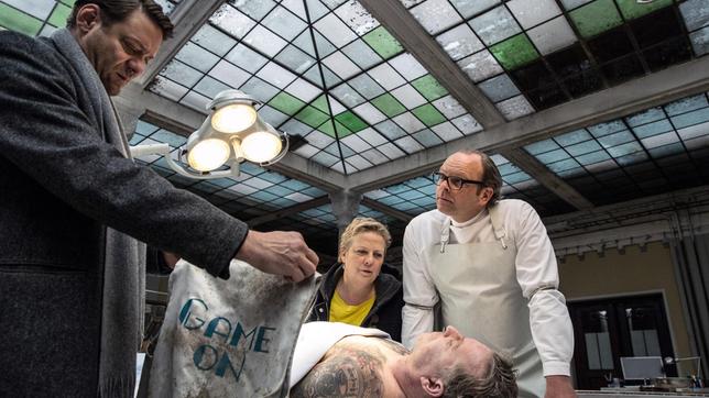 Bild: ARD Degeto/Hannes Hubach Jan Koller (Roeland Wiesnekker, li.), seine Kollegin Klára Majerova (Gabriela Maria Schmeide) und der Pathologe Dr. Jan Graupner (Andreas Schröders) untersuchen die Leiche des BKA-Beamten Frank Müller (Dirk Borchardt).