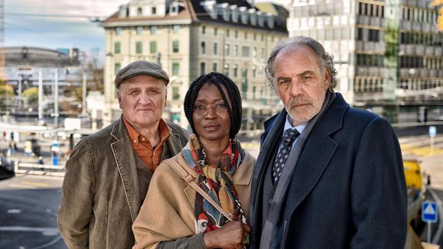 Bild: ARD Degeto/Patrick Pfeiffer Borchert (Christian Kohlund, re.) und sein Fahrer Bürki (Andrea Zogg) kümmern sich um Malia Baluba (Sheri Hagen)....
