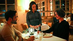 Tarik (Aram Arami) und Annika (Laura Louisa Garde, re.) haben etwas zu feiern. Mitte: Kellnerin Saskia (Tanya Erartsin).