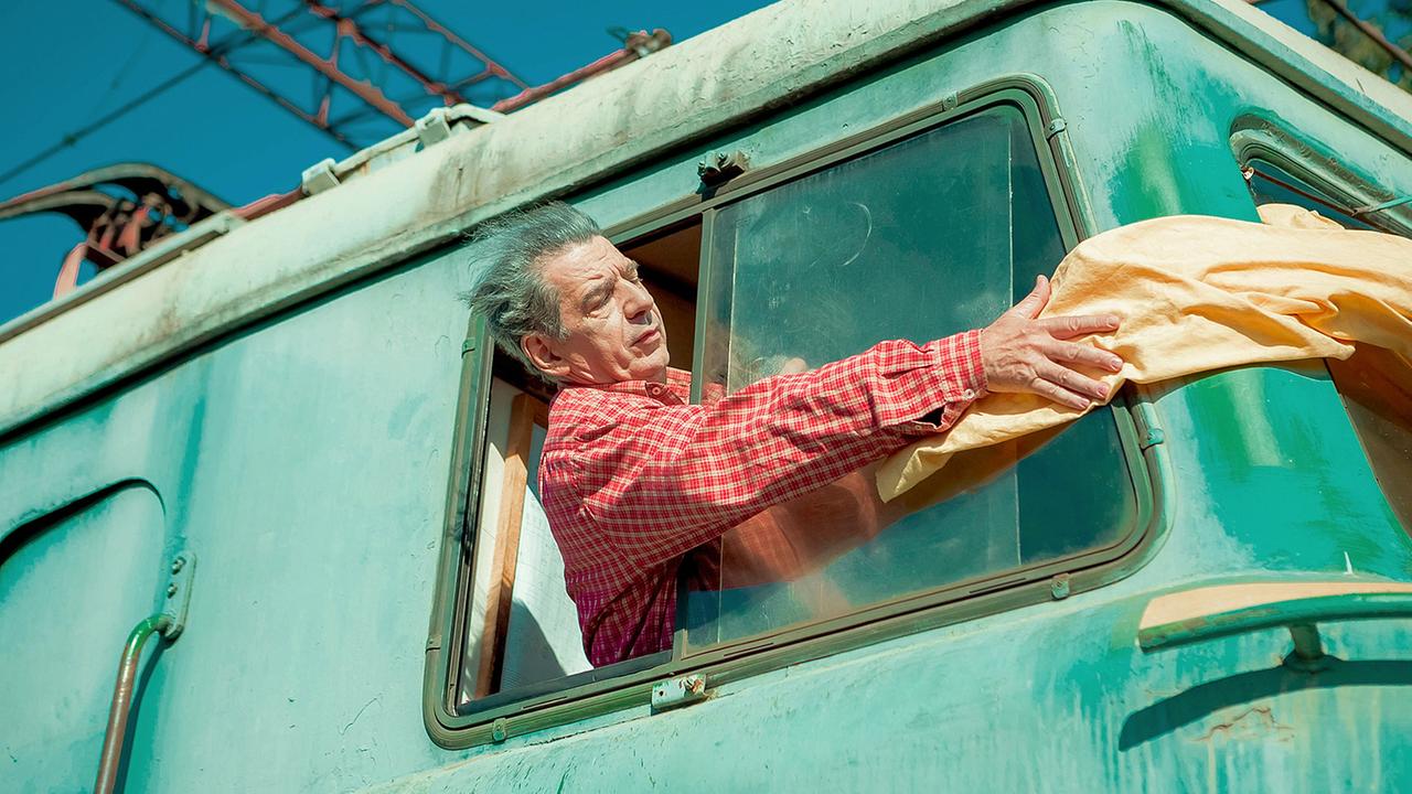 In dem dicht besiedelten Vorort Bakus passt der Zug jeden Tag um Haaresbreite zwischen den Haustüren hindurch. Das Schienenbett ist für die Bewohner ein kleiner Freiraum für Wäsche, Spiele und Geselligkeit. Predrag 'Miki' Manojlovic als Nurlan
