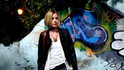 Annika Bengtzon vor einer mit Grafitti besprühten Mauer