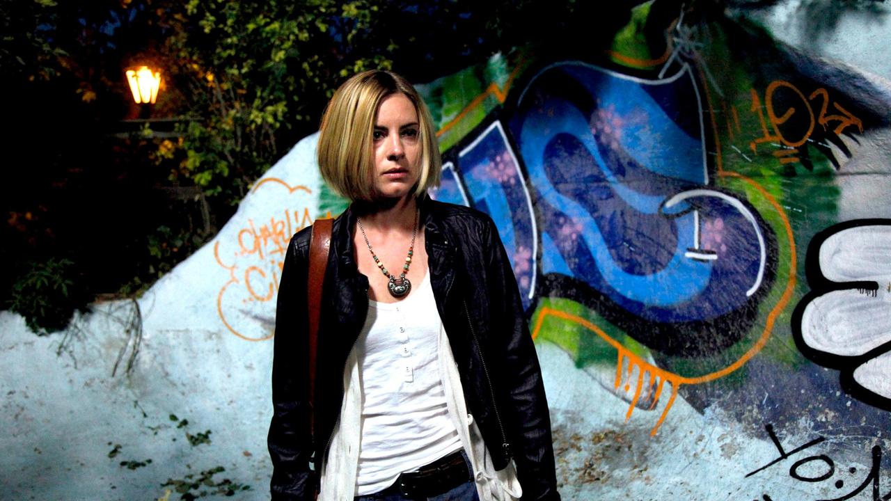 Annika Bengtzon vor einer mit Grafitti besprühten Mauer
