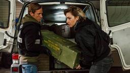 Chris Blome (Merlin Leonhardt) und Nina (Kim Riedle) laden Waffen aus dem Transporter.