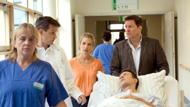 Bild: ARD/Volker Roloff David wird von Dr. Sandmann in den OP gebracht. Seine Freundin Sara und Dr. Kleist begleiten ihn (v.l.n.r. Komparsin, Luca Zamperoni, Susan Sideropoulos, Francis Fulton-Smith, vorne Patrick Diemling).