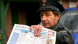 Der örtliche Polizist André (Thorsten Merten) präsentiert die Titelseite über das Verschwinden des kleinen Tobias.