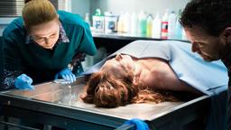 Detective Mike Shepherd (Neill Rea) und die Pathologin Gina (Cristina Serban Ionda, li.) untersuchen die Leiche von Debbie Neilson (Lara Macgregor).