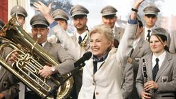 Mit der Organisation eines internationalen Festivals der Volksmusik gelingt der umstrittenen Bürgermeisterin Dorothee Auer (Nicole Heesters, Mitte) endlich der Durchbruch.