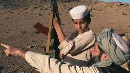 Routiniert weist der Vater (Sher Alam Miskeen Ustad), ein Büchsenmacher, seinen jungen Sohn (Niaz Khan Shinwari) in den Umgang mit Waffen ein.