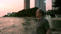 Holger Lenz steht am Strand und sieht dem Sonnenuntergang zu. 